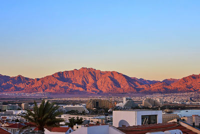 Panoramic shot of buildings and mountains against clear sky