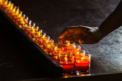 Cropped hand holding lit tea light in darkroom