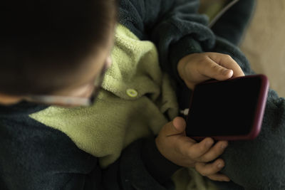 Closeup portrait of a boy who looks into phone sitting on floor, playing on the phone on charging