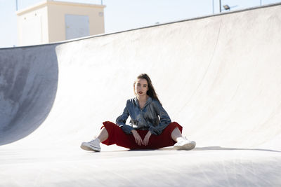 Portrait of young woman sitting on built structure