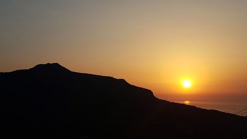 Scenic view of silhouette mountains against clear sky during sunset