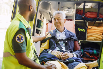 Male paramedic consoling mature patient in ambulance