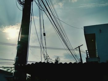 Low angle view of silhouette electricity pylon against sky