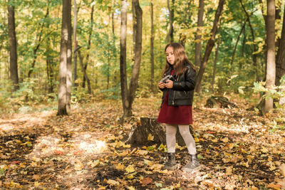 Full length of a young man using phone in forest