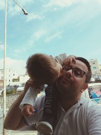 Portrait of young couple kissing against sky