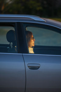 Senior elegant lady enjoying sunset from a car at the coast