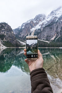 Close-up of hand holding lake against mountain range