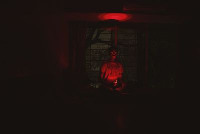 Young woman sitting in illuminated room