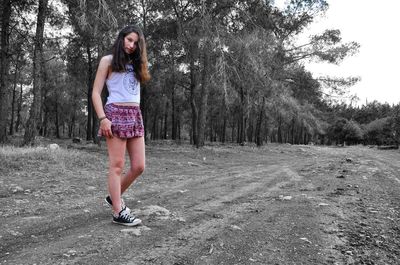 Full length of woman standing on tree trunk