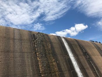 Low angle view of weathered wall against blue sky