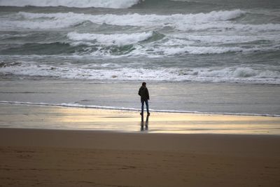Rear view full length of man standing on shore at beach