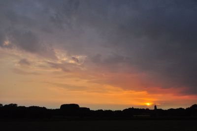 Scenic view of silhouette field against sky at sunset