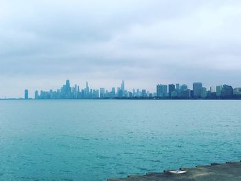 City skyline by sea against sky