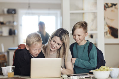 Happy mother with excited sons watching laptop at home