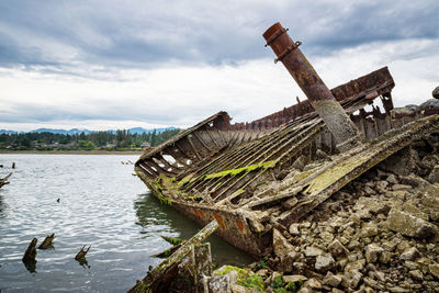 Abandoned built structure in lake against sky