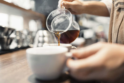 Cropped image of barista preparing coffee at counter