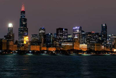 Illuminated buildings in city against sky at night