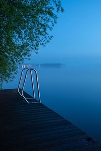 Pier on lake against clear blue sky