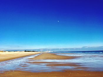 Scenic view of beach against clear blue sky