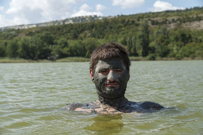 Portrait of man with mud on face in lake