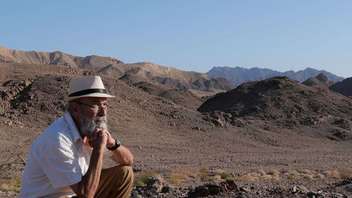 Senior man sitting in the desert 