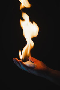 Close-up of burning candle against black background