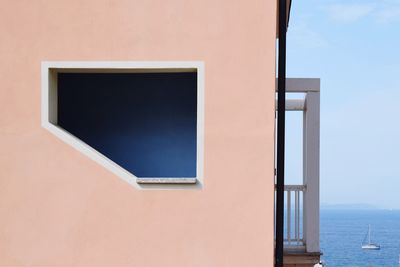 Close-up of window on building by sea against sky