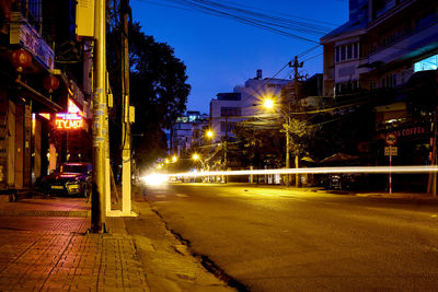 Illuminated street amidst buildings in city at night