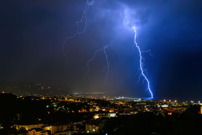 Lightning over illuminated buildings in city at night