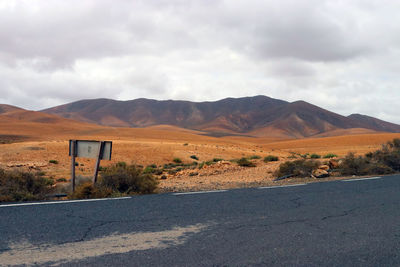 Scenic view of road by mountains against sky