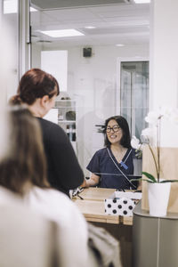 Smiling female receptionist assisting patient at checkout in medical clinic