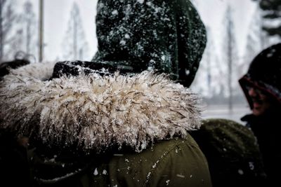 Close-up of person wearing fur coat during snowfall