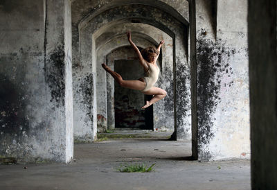 Full length of woman dancing in corridor of abandoned building