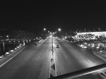 Road passing through illuminated city at night