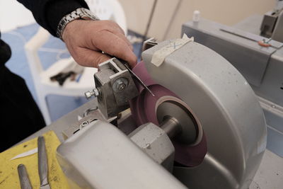 Cropped hand holding knife in machinery at factory