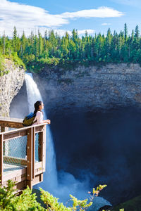 Rear view of woman standing against waterfall