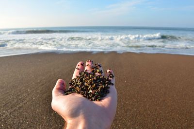 Close-up of hand holding sand on beach