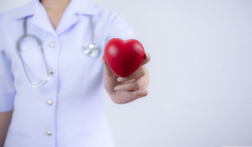 Close-up of woman holding heart shape over white background