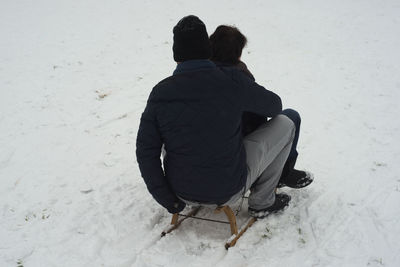 Couple sledding on snow covered field