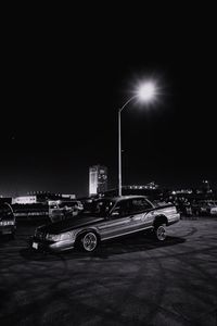 Cars on illuminated street against sky at night
