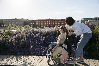 Woman pointing at flowers to daughter with disability on sunny day