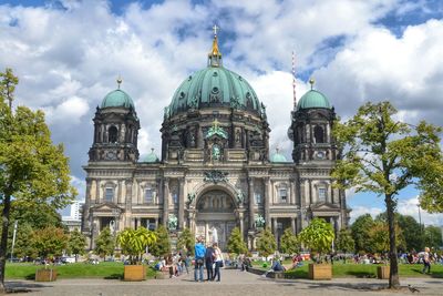 Tourists visiting berlin cathedral against cloudy sky