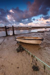 Boat moored on beach against sky