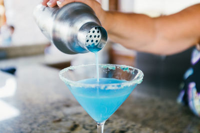 Cropped hand of female bartender preparing cocktail on counter