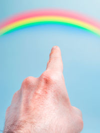 Close-up of human hand against rainbow