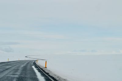 Road by sea against sky during winter