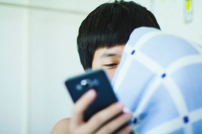Cropped image of teenage boy holding mobile phone at home