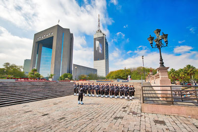 People standing by building against sky in city