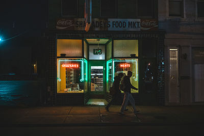 People walking on illuminated building at night