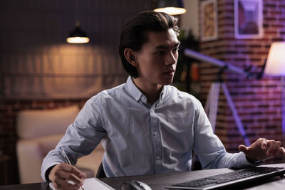 Side view of young man using laptop while sitting on table